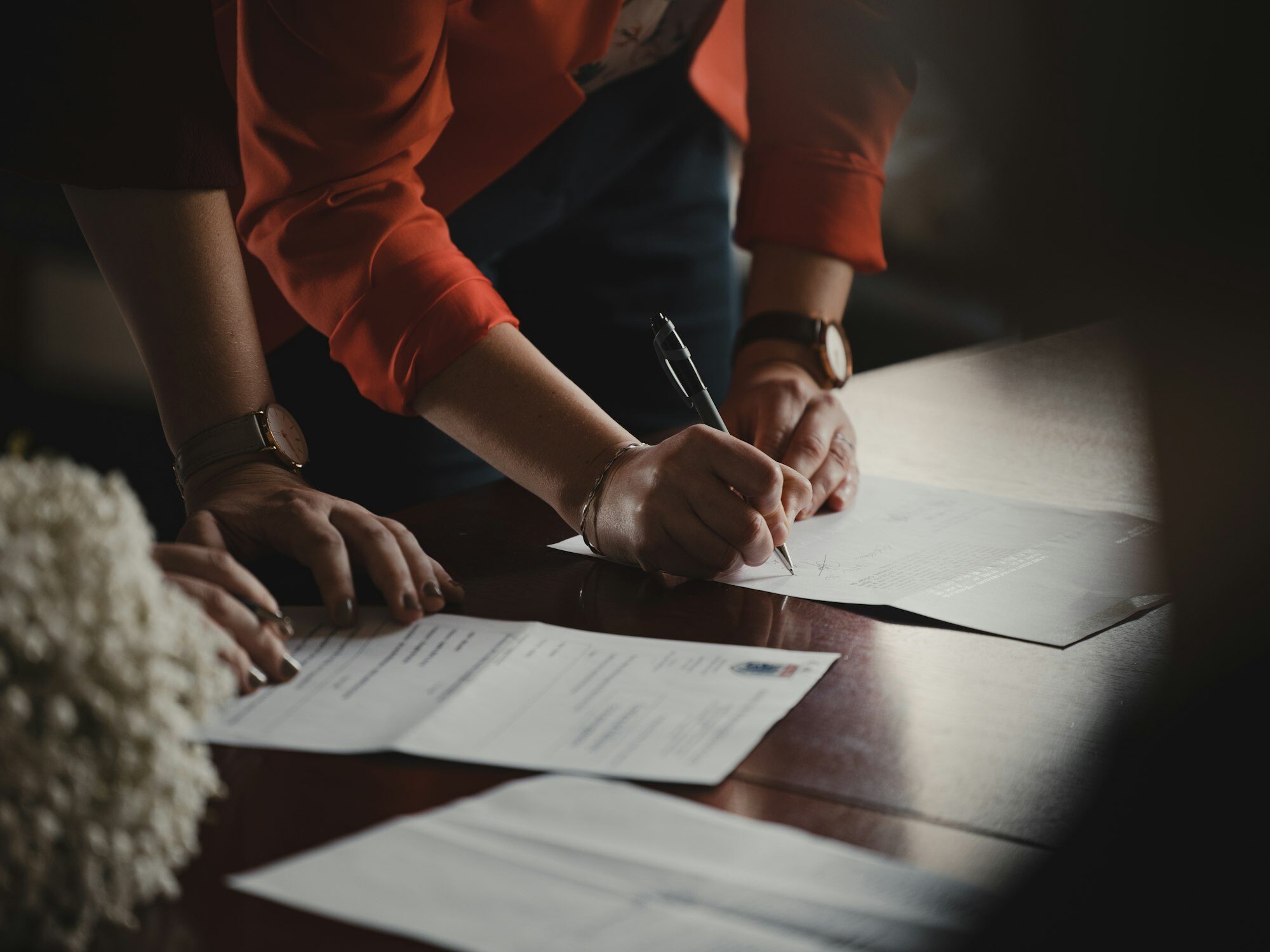 Two people completing and signing legal documents at a desk